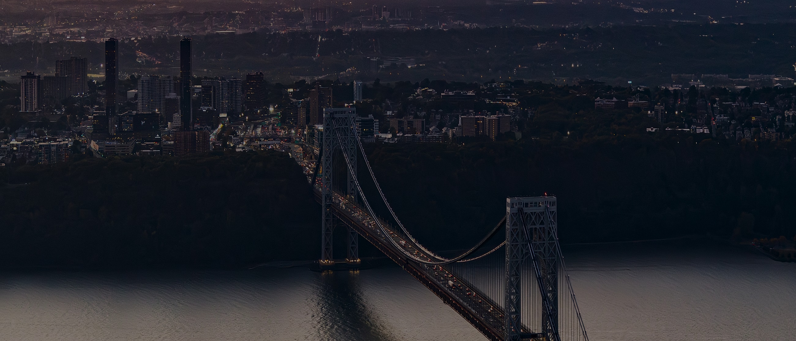 George Washington Bridge at night with city skyline.