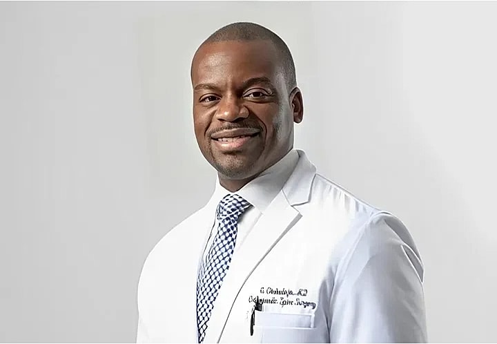 NYC & NJ spine surgeon, Dr. Okubadejo, in his scrubs smiling.
