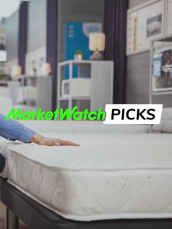 Person testing mattress in showroom environment.