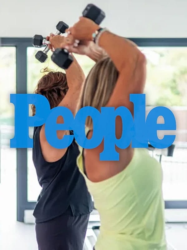 Women exercising with dumbbells in gym.