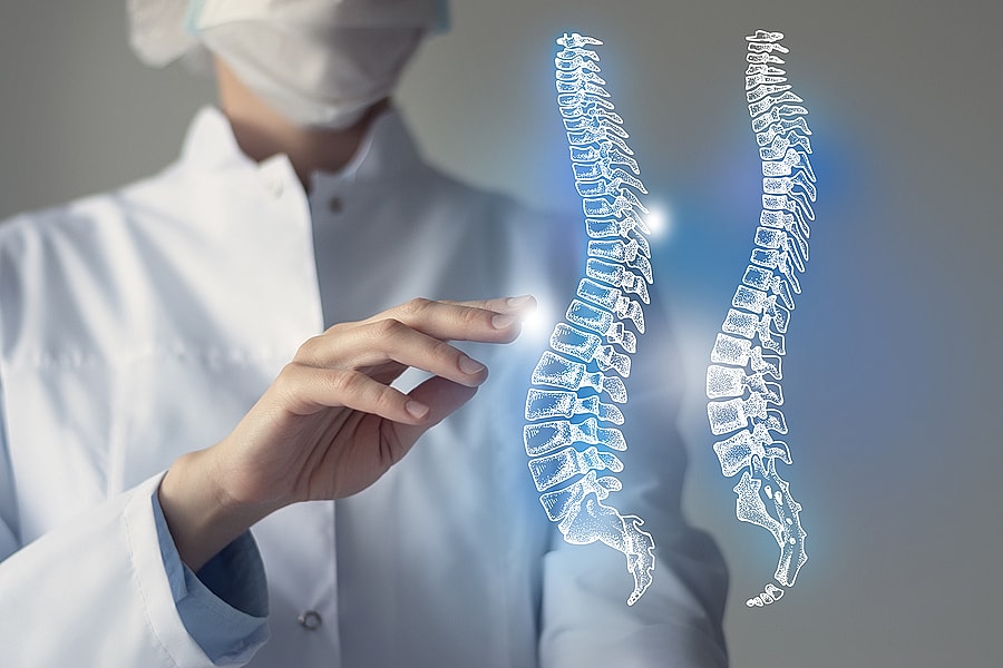 Medical professional examining holographic spine images.
