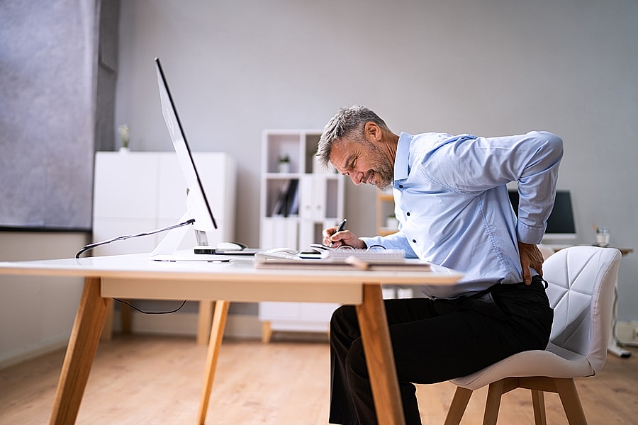 Man experiencing back pain while writing.