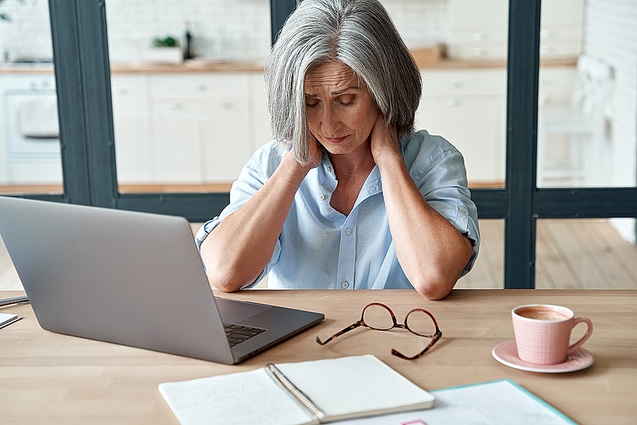 neck pain treatment patient model working on a laptop at home.