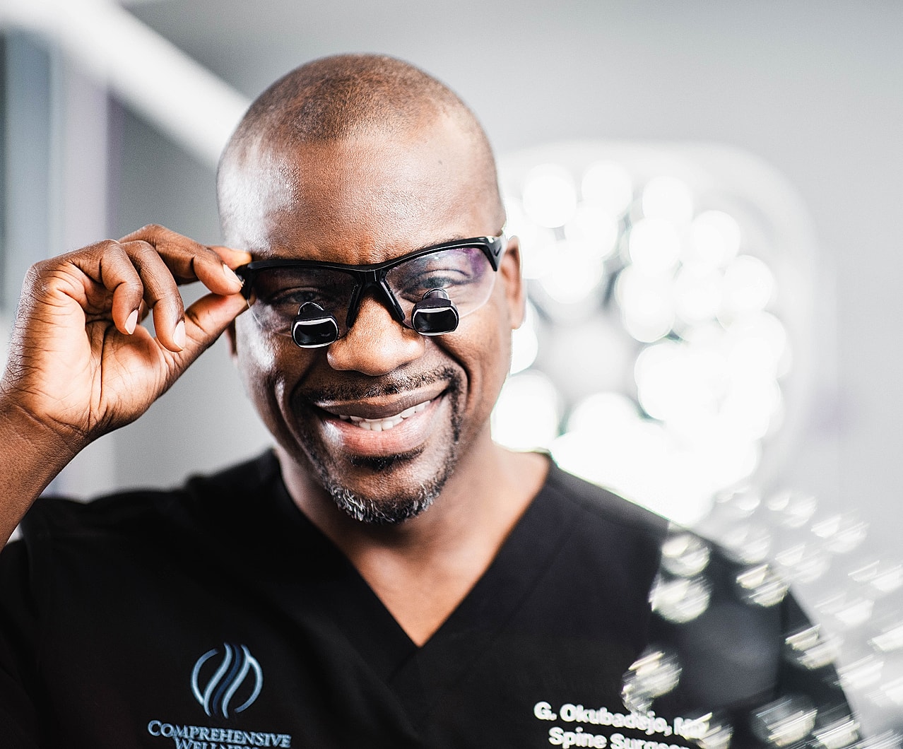 Smiling doctor adjusting medical glasses in clinic.