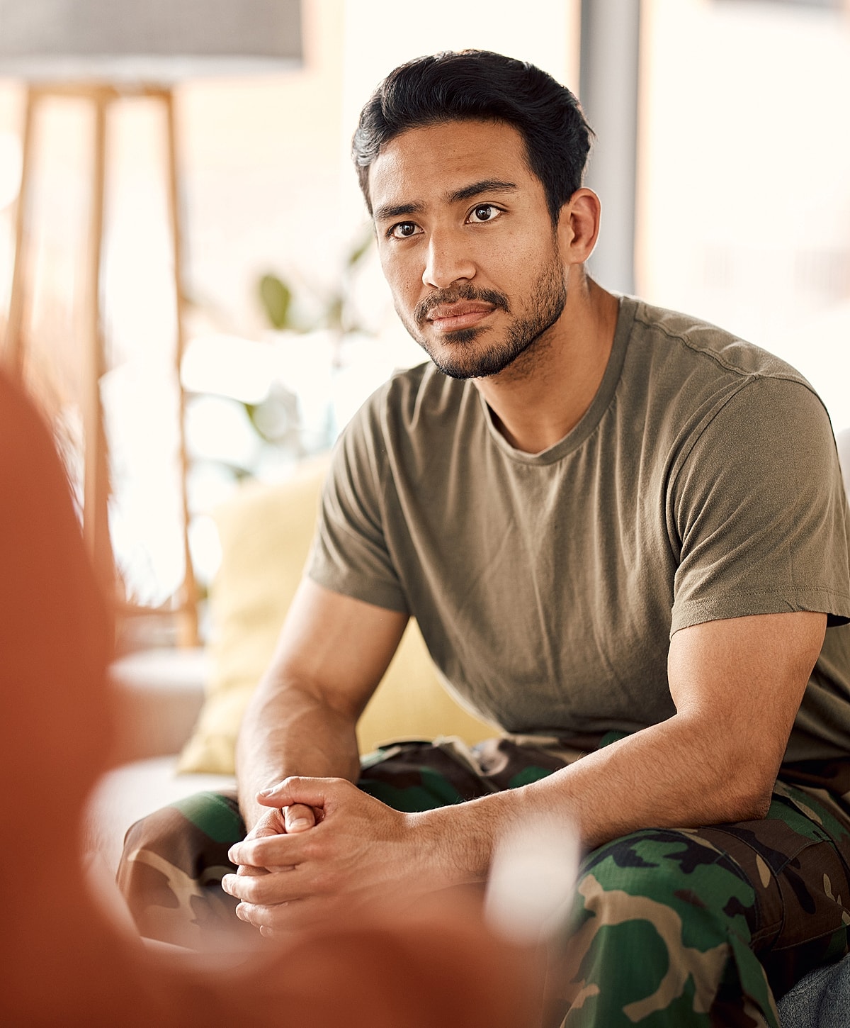lower back pain treatment patient model sitting, deep in thought indoors.