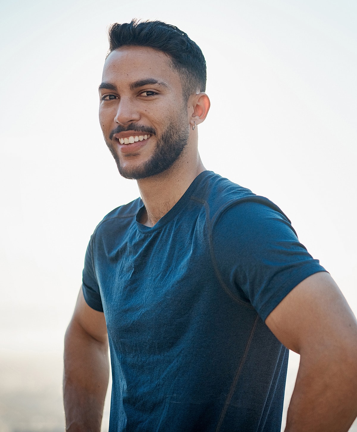 Smiling osteoarthritis treatment patient model in a blue shirt outdoors.