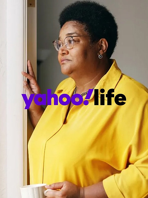 Woman in a yellow shirt holding a cup.