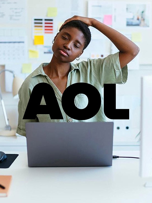 Woman stretching while working on laptop.