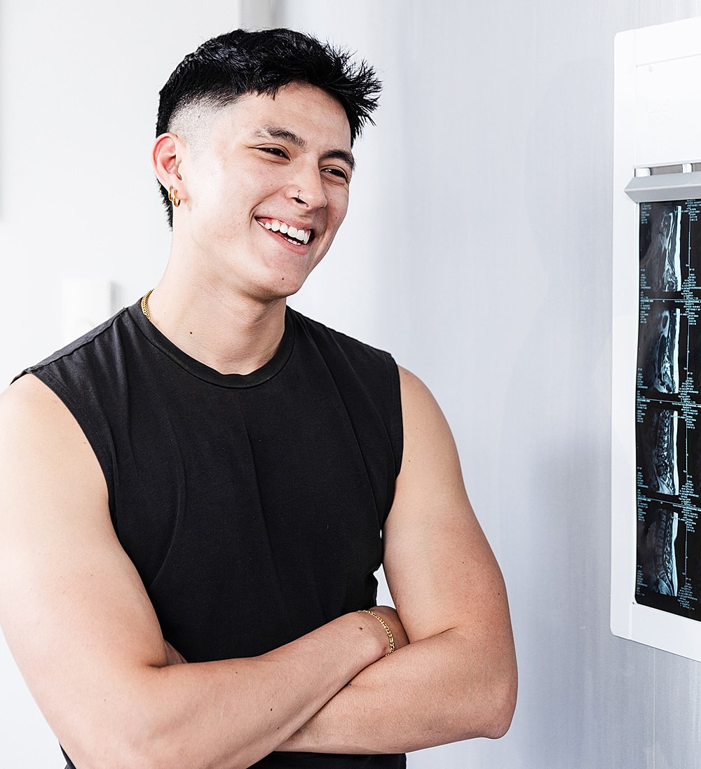 Smiling lumbar microdiscectomy patient model in sleeveless shirt by X-ray images.