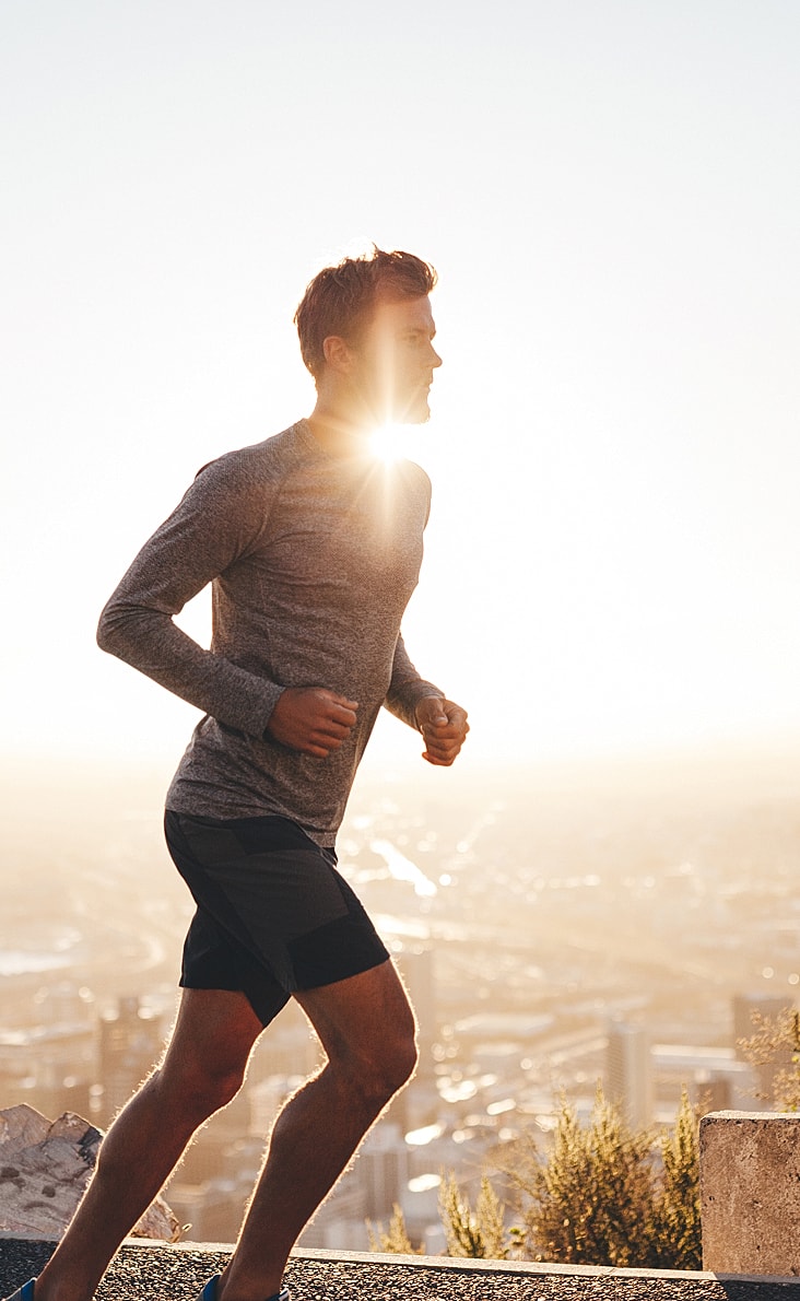 Runner in sunlight against a city backdrop.