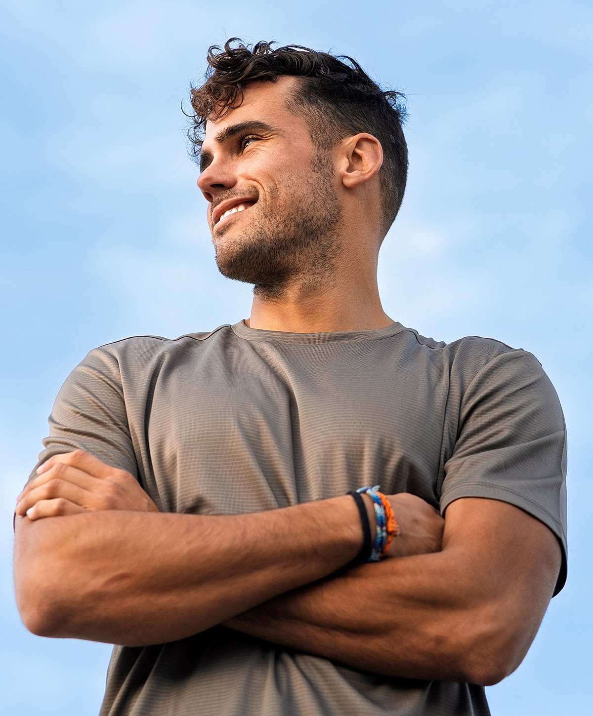 Smiling endoscopic lumbar discectomy patient model with arms crossed outdoors against sky.