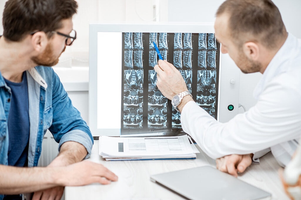 Doctor discussing spinal X-ray images with patient.