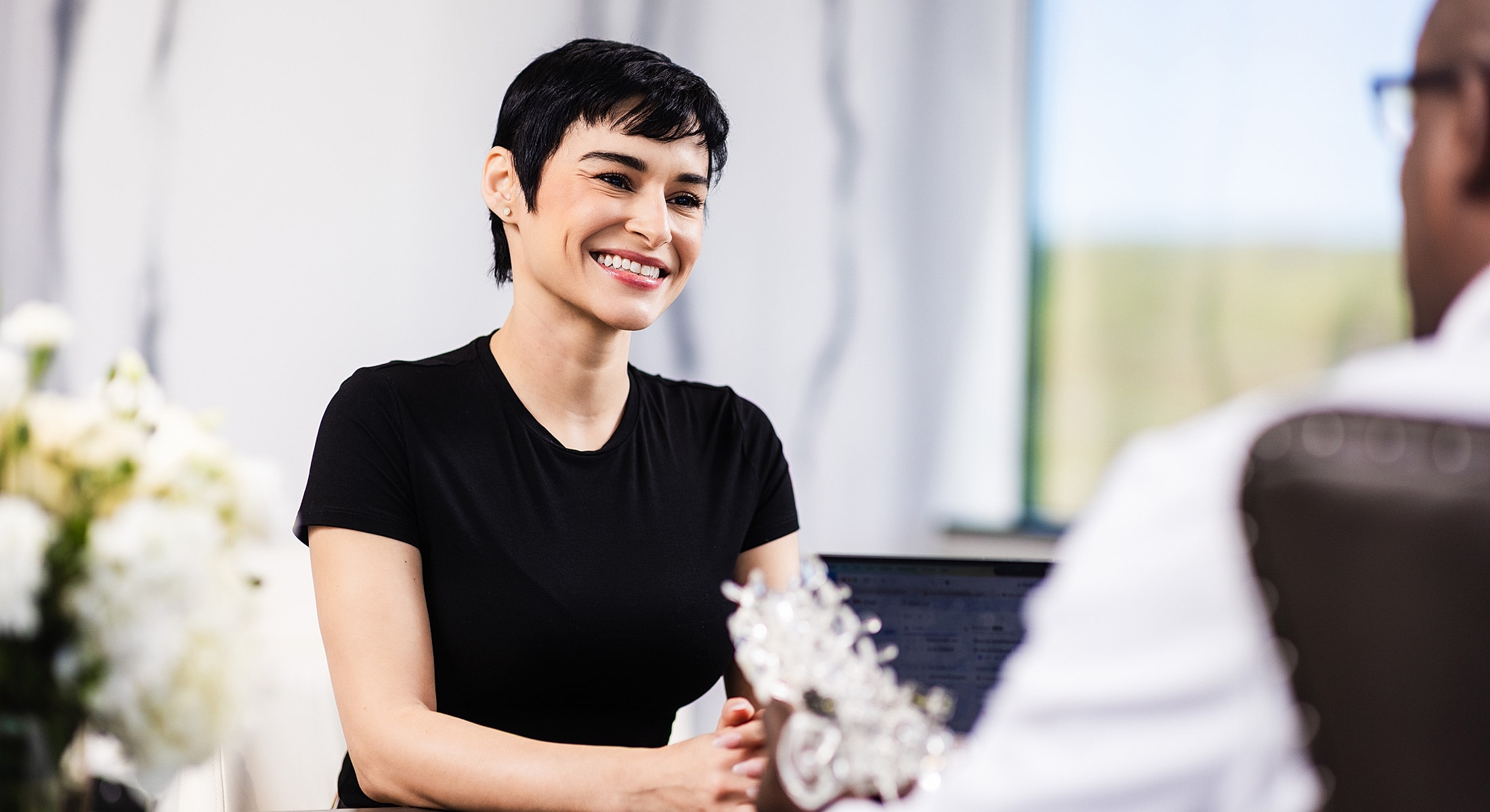 spinal stenosis treatment patient model smiling in a professional conversation setting.