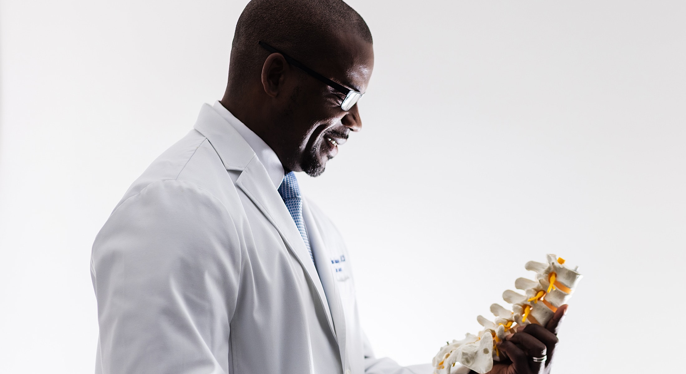 spine surgeon examining a spinal model with smile.